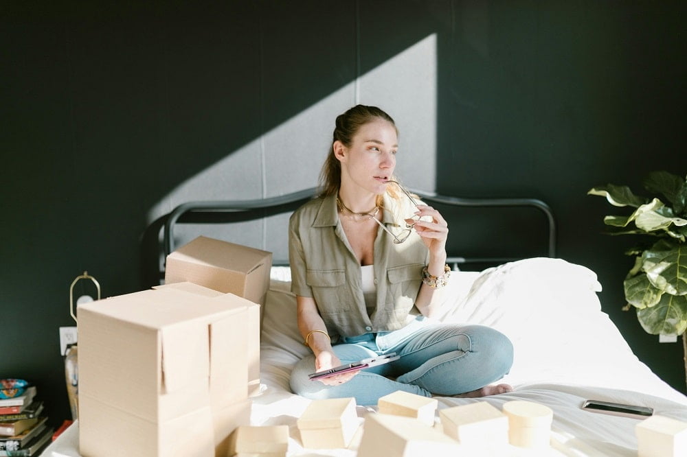 a woman sitting among boxes and understanding what dropshipping is