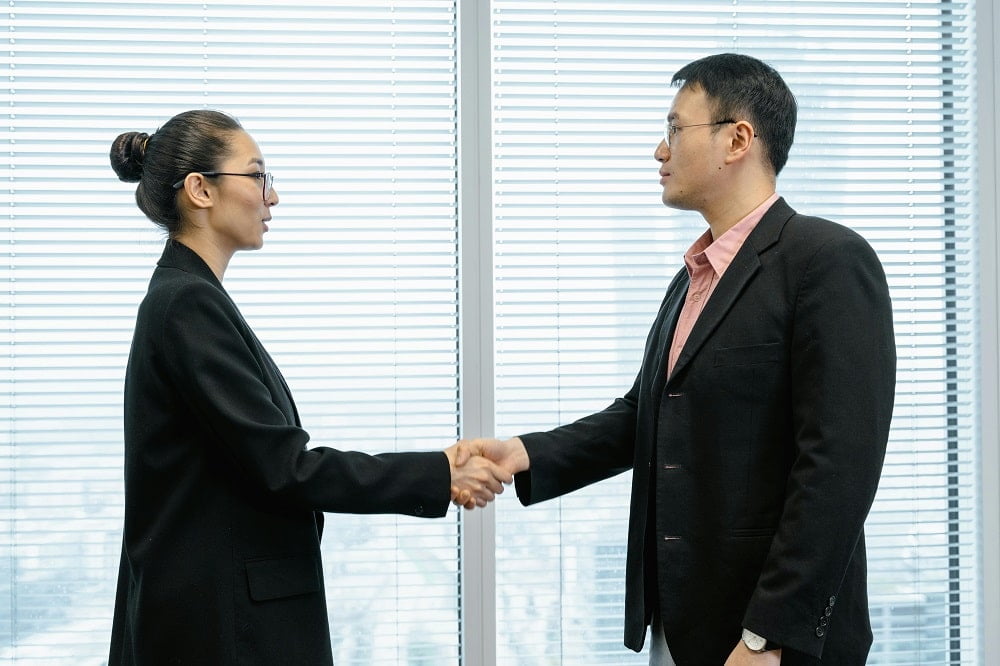 a woman and a man shake hands after a strategic negotiation
