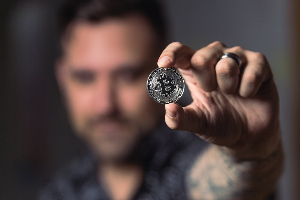 a man holding a coin symbol of crypto trading
